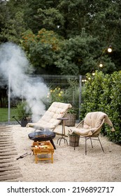 Atmospheric Backyard With Fire And Lounge Chairs At Dusk On Nature. Grilling Food On Fire Bowl