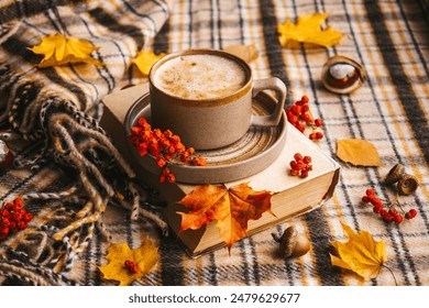 Atmospheric cozy autumn composition. Hot mug of coffee, book, fall leaves, chestnut, ashberry, acorns and cozy brown plaid as background. Sunday loneliness relaxing, hugge mood. Thanksgiving day. - Powered by Shutterstock