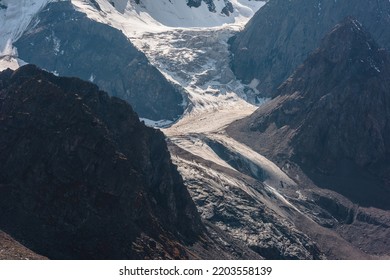 Atmospheric landscape with large snow mountain range in sunny day. Glacier and icefall in bright sun among sharp rocks. Awesome mountain view to high snowy mountains. Sunlit beautiful icefall close-up