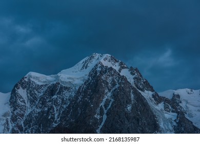 Atmospheric nightly landscape with huge snowy mountain top in dramatic sky. Hanging glacier and cornice on beautiful giant snow mountains in night. High snow-covered mountain range in dusk dim light. - Powered by Shutterstock