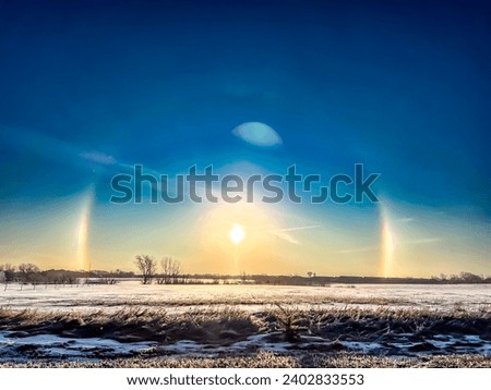 Atmospheric optical phenomenon sun dogs in the morning across a snow field. 