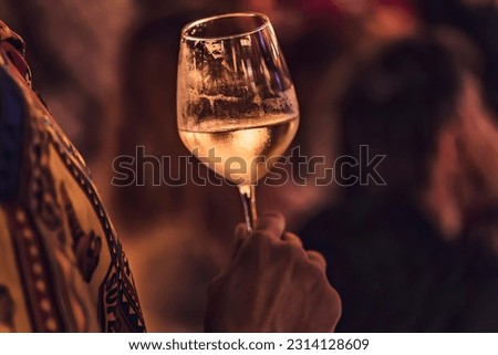 An atmospheric photo showcasing a wine glass in a local setting at night.