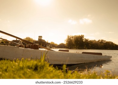 Atmospheric view of a solitary wooden punt seen on a public lake shoreline on a warm autumns day. - Powered by Shutterstock