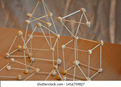 The atom model is made of supportive materials. Molecular grid of toothpicks and nuts. School scientific exhibition.