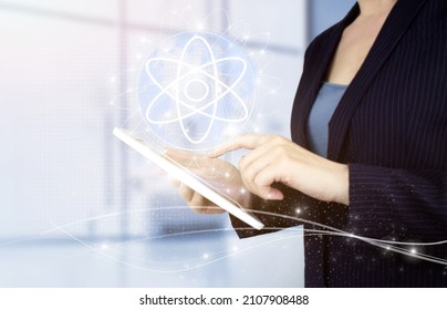 Atom molecule as concept for science. Hand touch white tablet with digital hologram molecule atom sign on light blurred background