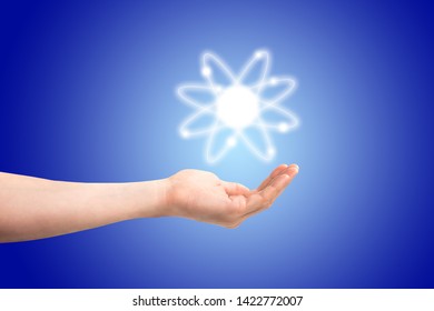Atom structure model in a hand with nucleus and electrons, technological concept of nuclear power. Flat illustration on blue background