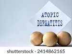 ATOPIC DERMATITIS - words on a white piece of paper on a white background with wooden balls. Info concept