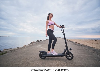Atractive happy woman is enjoying morning riding with her new electrical scooter at seaside. - Powered by Shutterstock
