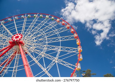Atraktsion Ferris wheel against a blue sky with clouds
