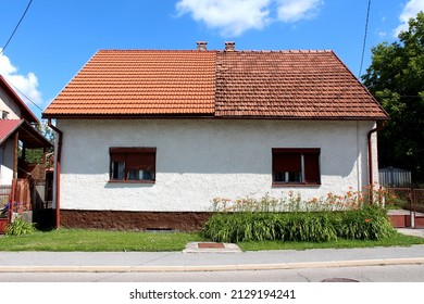 Attached small suburban family house with two owners split in the middle with left half covered with new red roof tiles and right one with dilapidated old roof tiles built next to paved - Shutterstock ID 2129194241