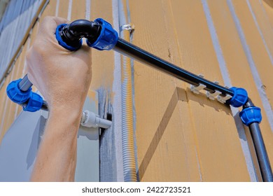 Attaching an angle pipe fitting with a compression threaded clamp to domestic outdoor water supply system for watering and irrigation, assembled from HDPE pipes.