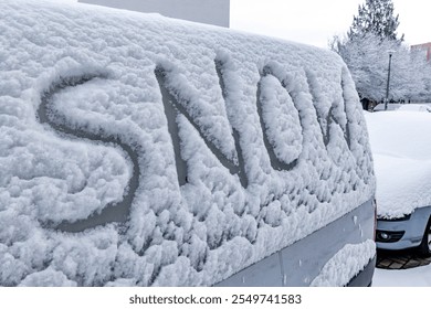 The attack of winter, the first snowfall, the word snow written on the car body in the snow