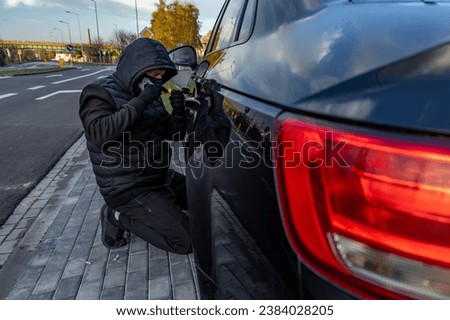 Attempted to steal a car using a suitcase in the city center - a thief in a hood with a mask on his face