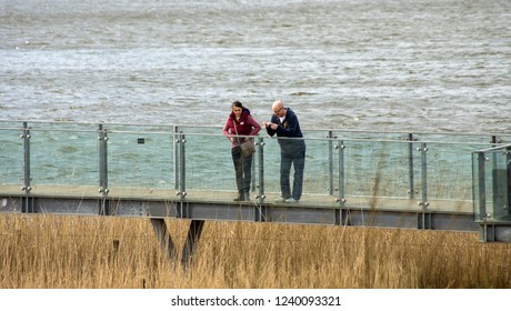 Attenborough, Nottinghamshire, UK 03/12/2015 Man And Woman On A Glass Footbridge Overlooking Reed Beds At A Nature Reserve