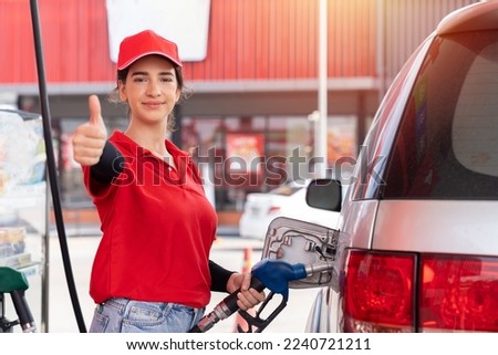 Attendant service female worker refuelling car at gas station. Assistant woman worker wear red uniform and red hat refuelling car at petrol station