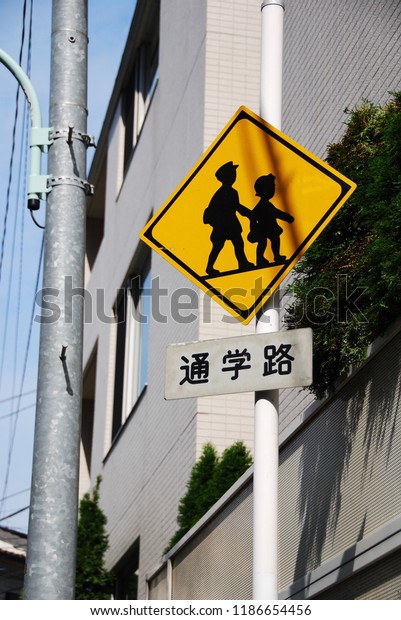 Attention sign for children in\
Tokyo, Japan, is set in a community for awareness while driving a\
car in a school zone. The Japanese text means \