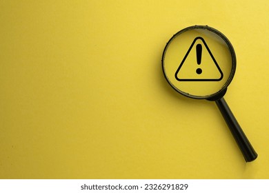 Attention sign,Exclamation mark,warning sign concept.,Magnifying glass focus on Hazard warning attention sign icon over yellow background with copyspace. - Shutterstock ID 2326291829