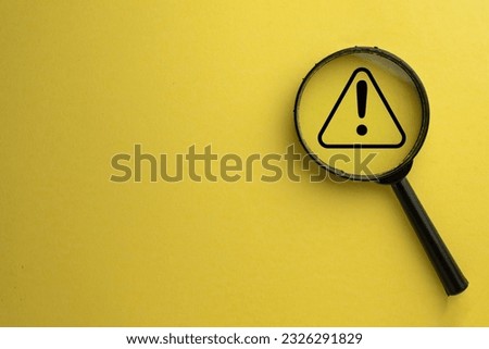 Attention sign,Exclamation mark,warning sign concept.,Magnifying glass focus on Hazard warning attention sign icon over yellow background with copyspace.