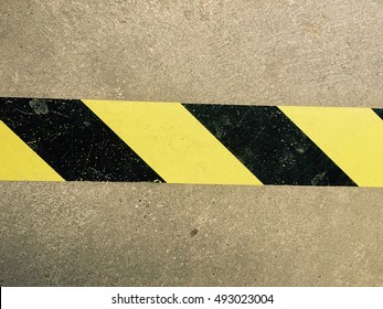 Attention. Warning Tape Yellow And Black On A Concrete Floor. Danger.