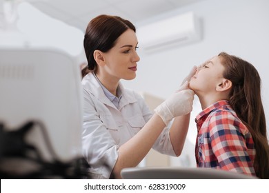 Attentive ENT Doctor Doing Nose Exam Of Her Daughter