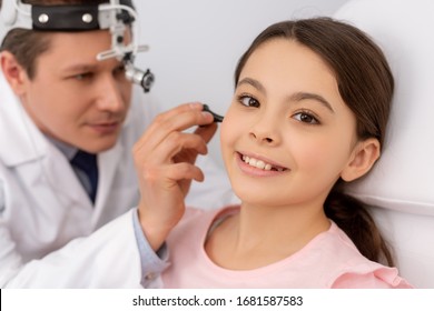 Attentive Ent Physician Examining Ear Of Smiling Child With Ear Speculum