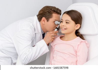 Attentive Ent Physician Examining Ear Of Smiling Kid With Otoscope