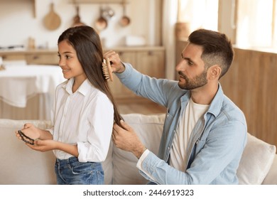 Attentive father brushing his daughters hair, demonstrating care and parental love in everyday life - Powered by Shutterstock