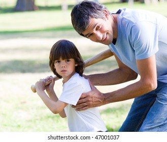 Attentive Father Playing Baseball With His Son In The Park