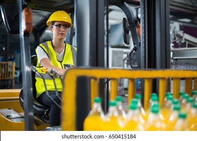 Attentive female factory worker driving forklift in factory - Powered by Shutterstock