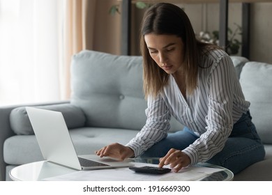 Attentive female student planning to pay college loan study financial papers count sum of regular payment to provide via electronic bank. Focused young businesswoman manage income calculate tax rates