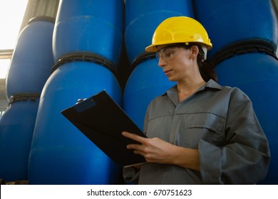 Attentive female worker writing on clipboard in olive factory - Powered by Shutterstock