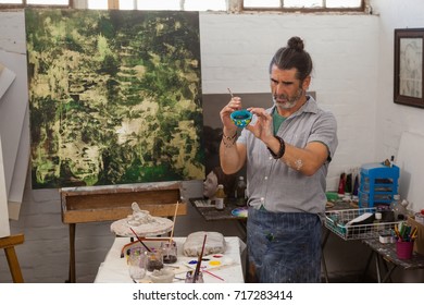 Attentive man painting bowl in class - Powered by Shutterstock