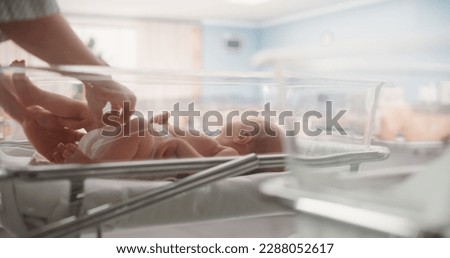Attentive Mother Changing Diaper to a Newborn Baby. Neonate Child Lying in a Hospital Crib in a Nursery Clinic Facility. Motherhood, Childhood and Medical Concept