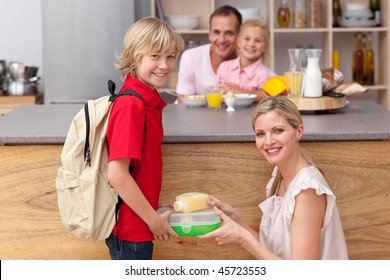 Attentive Mother Packing The School Lunch To His Son In The Kitchen