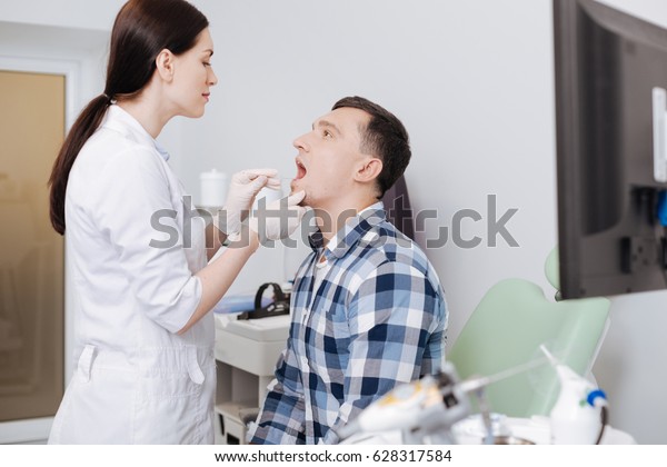 Attentive\
otolaryngologist doing throat\
exam