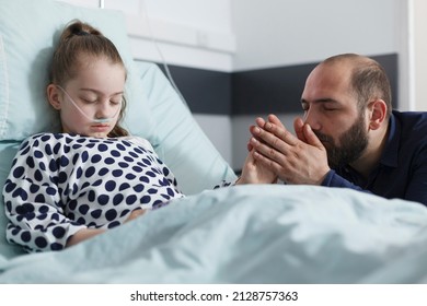 Attentive sad worried father holding unwell hospitalized daughter hand while in pediatric hospital room. Sleeping ill girl kid in clinic bed while caring anxious parent holding her hand. - Powered by Shutterstock