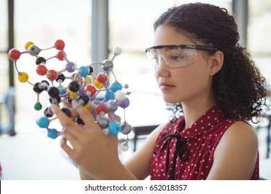 Attentive schoolgirl experimenting molecule model in laboratory at school - Powered by Shutterstock