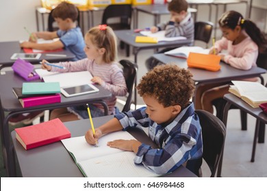 Attentive schoolkids doing their homework in classroom at school