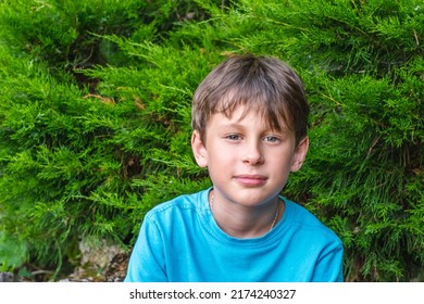 Attentive With A Slight Smile Of A 9-year-old Boy. Portrait Of A White Eastern European Boy In Nature