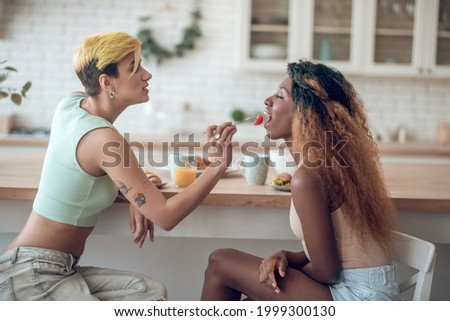 Attentive woman nursing flirtatious dark-skinned girlfriend