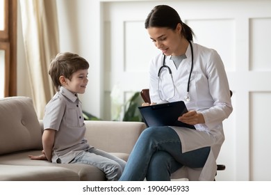 Attentive Young Caucasian Woman Doctor Or Pediatrician Consult Little Boy Patient At Home Visit. Caring Female Nurse Or GP Talk Have Consultation With Small Child In Hospital. Healthcare Concept.