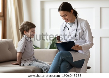 Attentive young Caucasian woman doctor or pediatrician consult little boy patient at home visit. Caring female nurse or GP talk have consultation with small child in hospital. Healthcare concept.