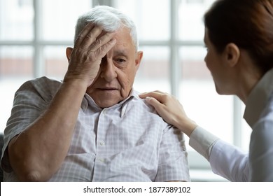 Attentive Young Lady Physician Interview Senior Patient On Meeting Listen To Complaints Make Diagnosis. Stressed Sad Elderly Man Visit Trusted Capable Doctor Feel Headache Dizzy Problems With Memory