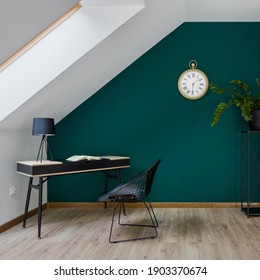 Attic home office room with simple desk and chair and big golden clock on emerald green wall - Shutterstock ID 1903370674