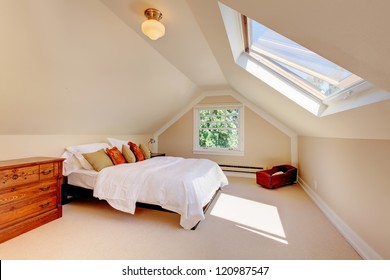 Attic modern bedroom with white bed and skylight and beige walls and carpet.