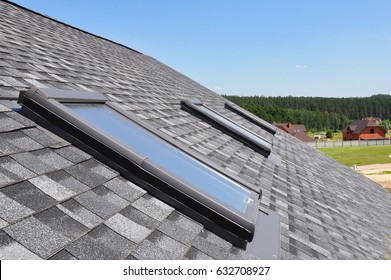 Attic skylight. Asphalt Shingles House Roofing Construction with Attic Roof windows, skylights waterproofing.