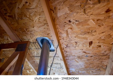 Attic view of installation of a galvanized vent pipe through a roof.