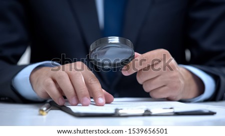 Attorney reading document with magnifier, studying case in detail, investigation