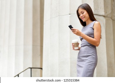 Attorney - young asian woman lawyer looking at mobile smartphone and drinking coffee from disposable paper cup. Young multiethnic female professional in the city in front of courthouse.