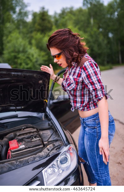 Attractie woman in
front of broken car's
engine